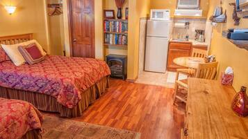 A bedroom with a large bed, a wooden dresser, a small table, and a bookshelf.