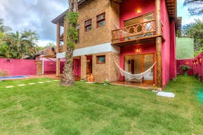 A two-story building with a red exterior, a balcony with a wooden railing, and a hammock outside. - Raio de Sol Pousada (Itacaré)