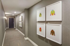A hallway with a carpeted floor and framed artwork on the walls. - The Sire Hotel Lexington,tapestry Collection by Hi (Lexington)