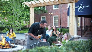 An outdoor seating area with a fire pit, a pergola, and a brick building with a sign that reads "The Sire Hotel". - The Sire Hotel Lexington,tapestry Collection by Hi (Lexington)