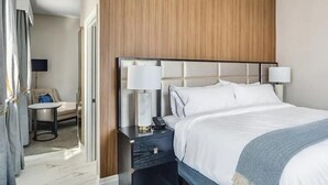 A hotel room with a large bed, two bedside lamps, a small table with a chair, and a TV. - The Sire Hotel Lexington,tapestry Collection by Hi (Lexington)