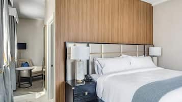A hotel room with a large bed, two bedside lamps, a small table with a chair, and a TV.