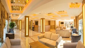 A spacious lobby with a reception desk, comfortable seating areas, and a modern chandelier. - Rich Melissa Hotel (Kemer)