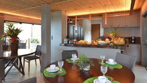 A modern kitchen with a central island, stainless steel appliances, and a dining area with a round table and chairs. - Pousada Maria Bonita Noronha (Fernando de Noronha)