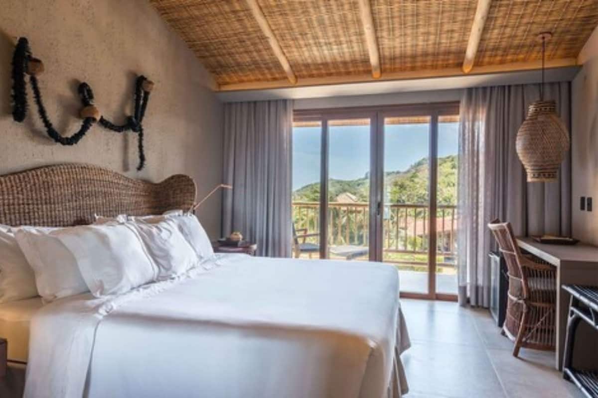 A bedroom with a large bed, a desk, and a view of the outdoors.
