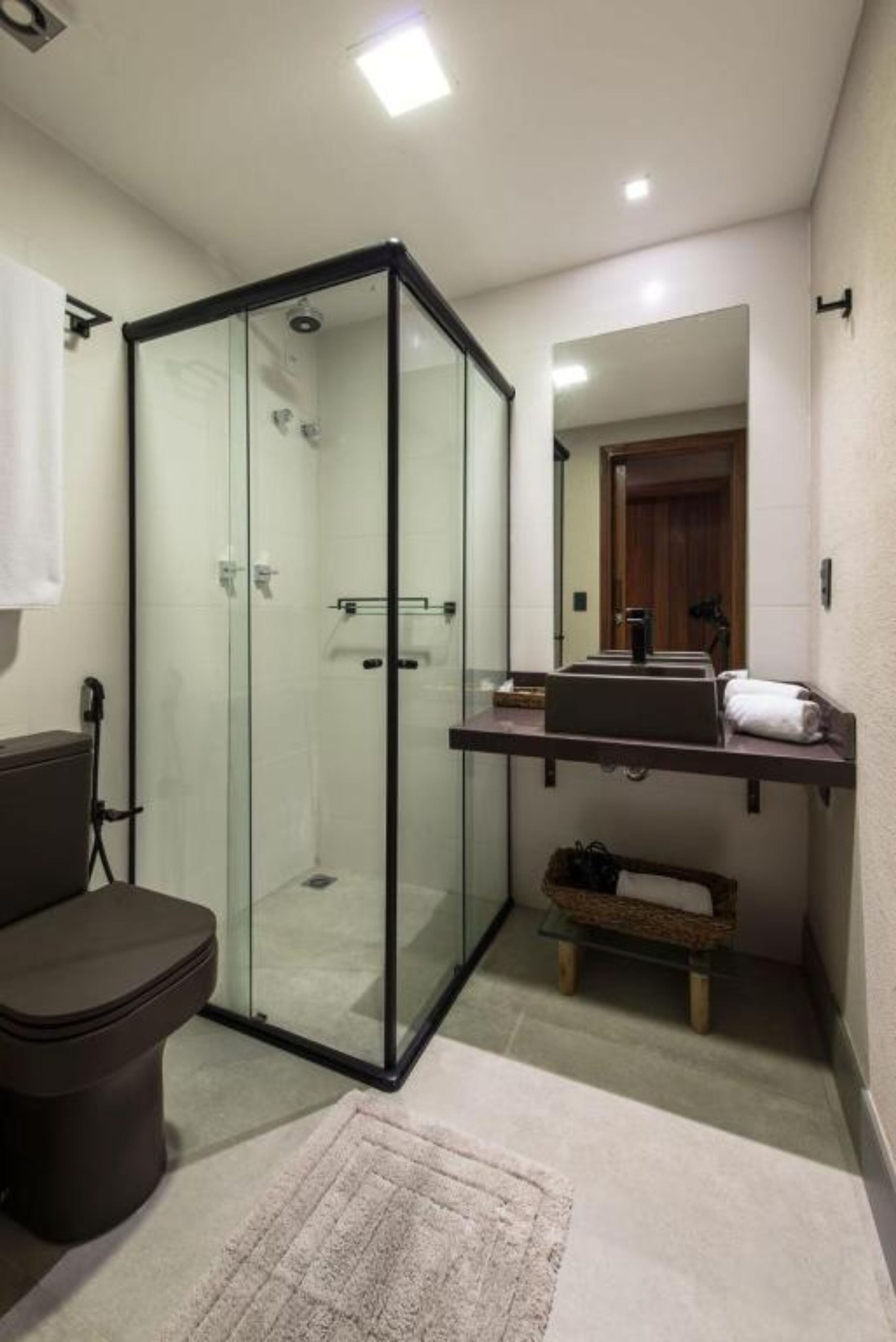 Ein modernes Badezimmer mit einer gläsernen Dusche, einer Toilette und einem Waschtisch mit Handtuchhalter.