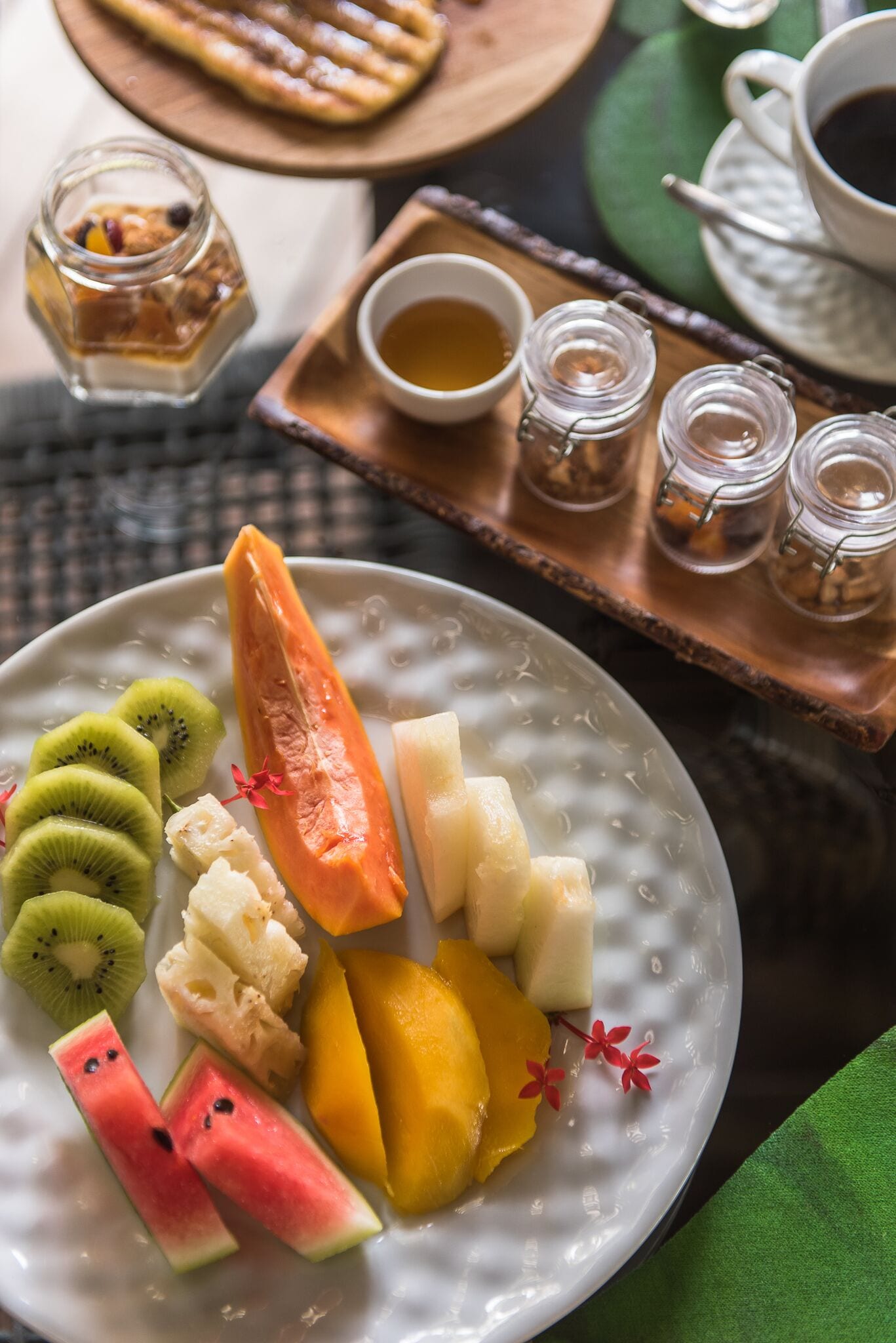 A plate of assorted fruits and a cup of tea on a table.