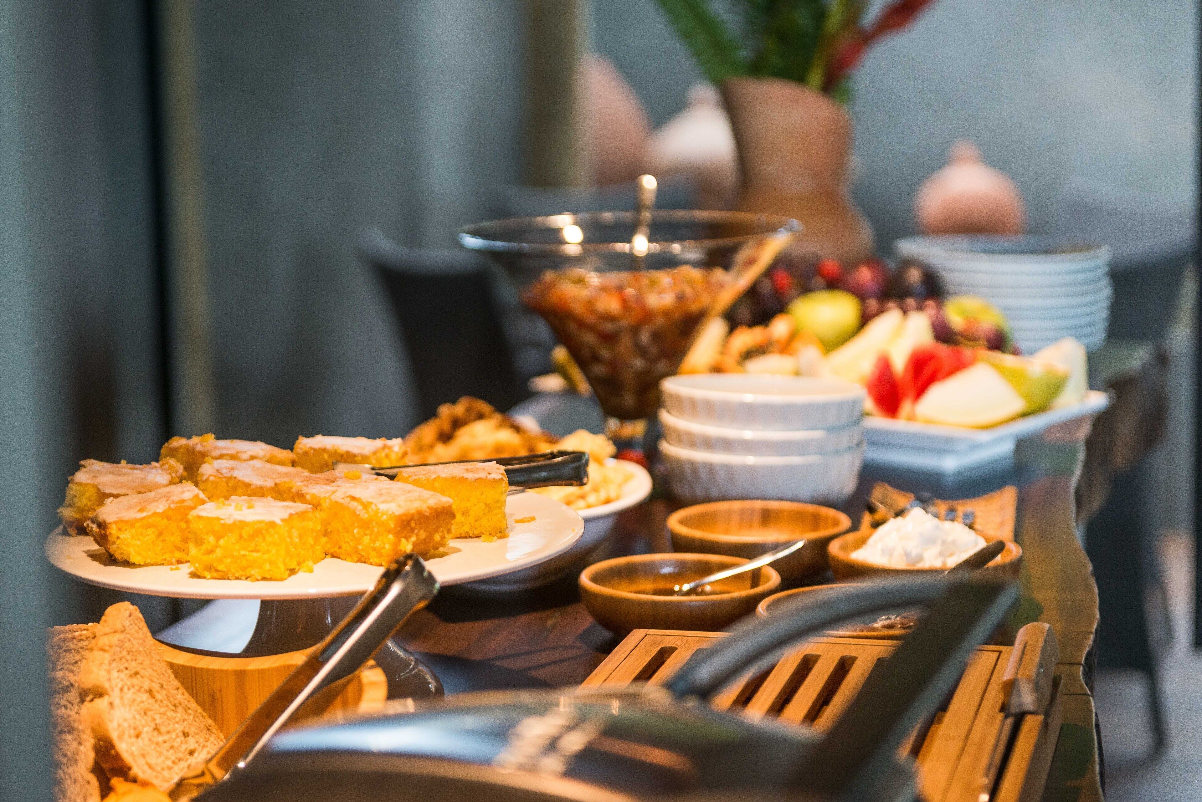 Une table de buffet proposant divers plats, notamment des gâteaux, des fruits et un saladier rempli de fruits.