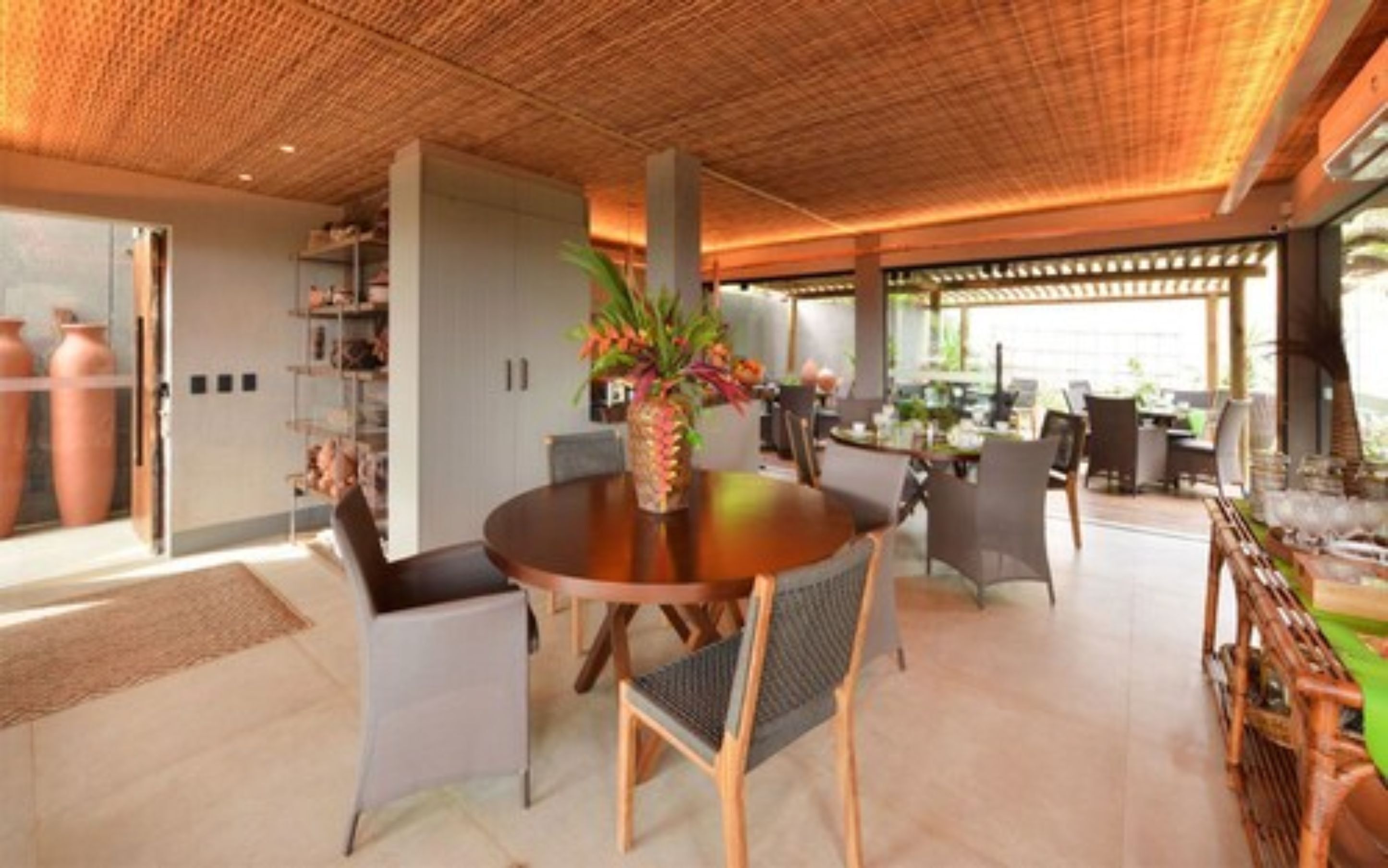 A modern dining area with a round table, chairs, and a decorative plant centerpiece.