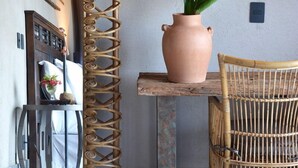A room with a woven partition, a potted plant, a wicker chair, and a wooden table. - Pousada Maria Bonita Noronha (Fernando de Noronha)