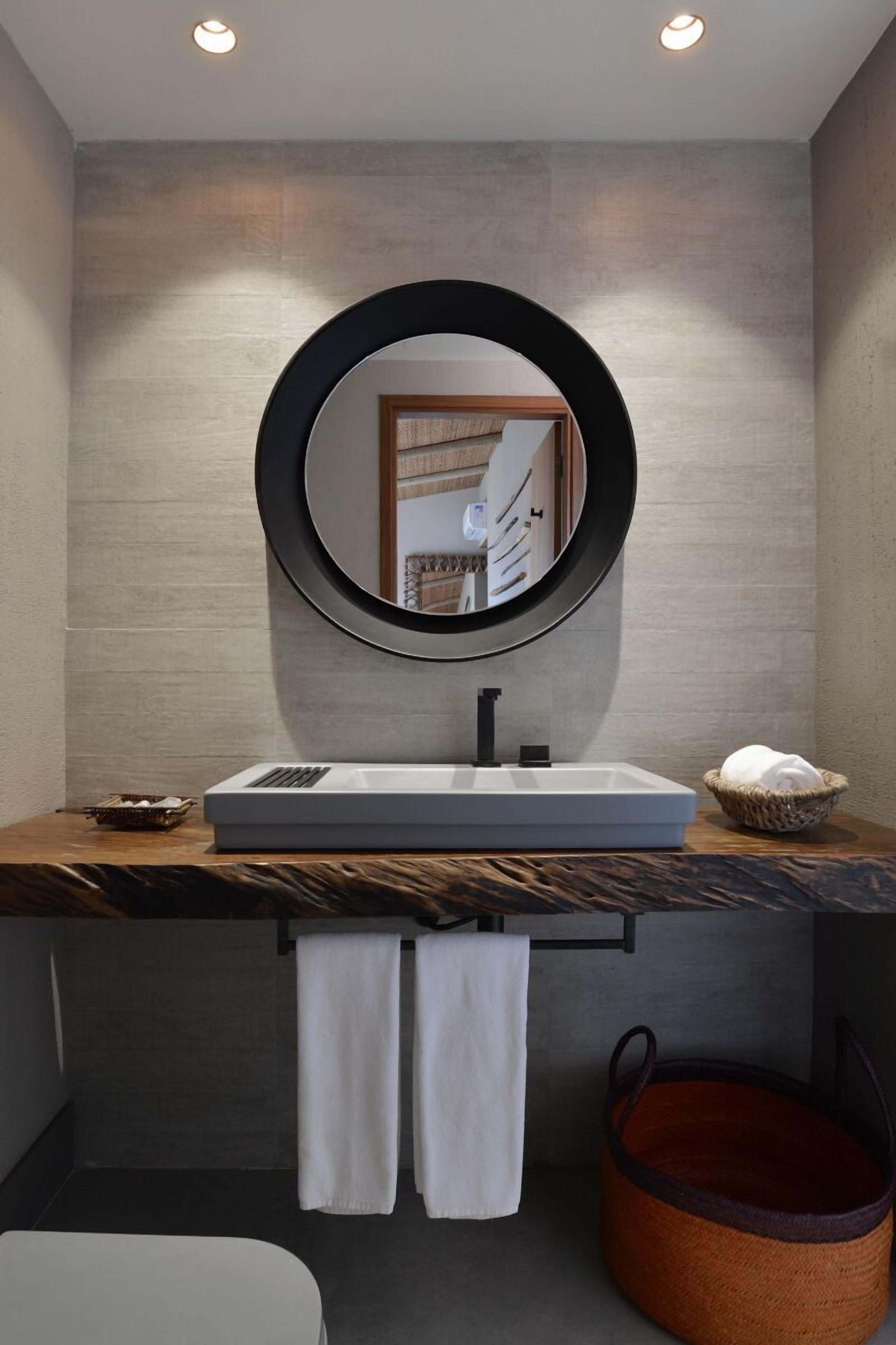 Un baño moderno con un lavabo rectangular, un espejo redondo y un perchero para toallas.