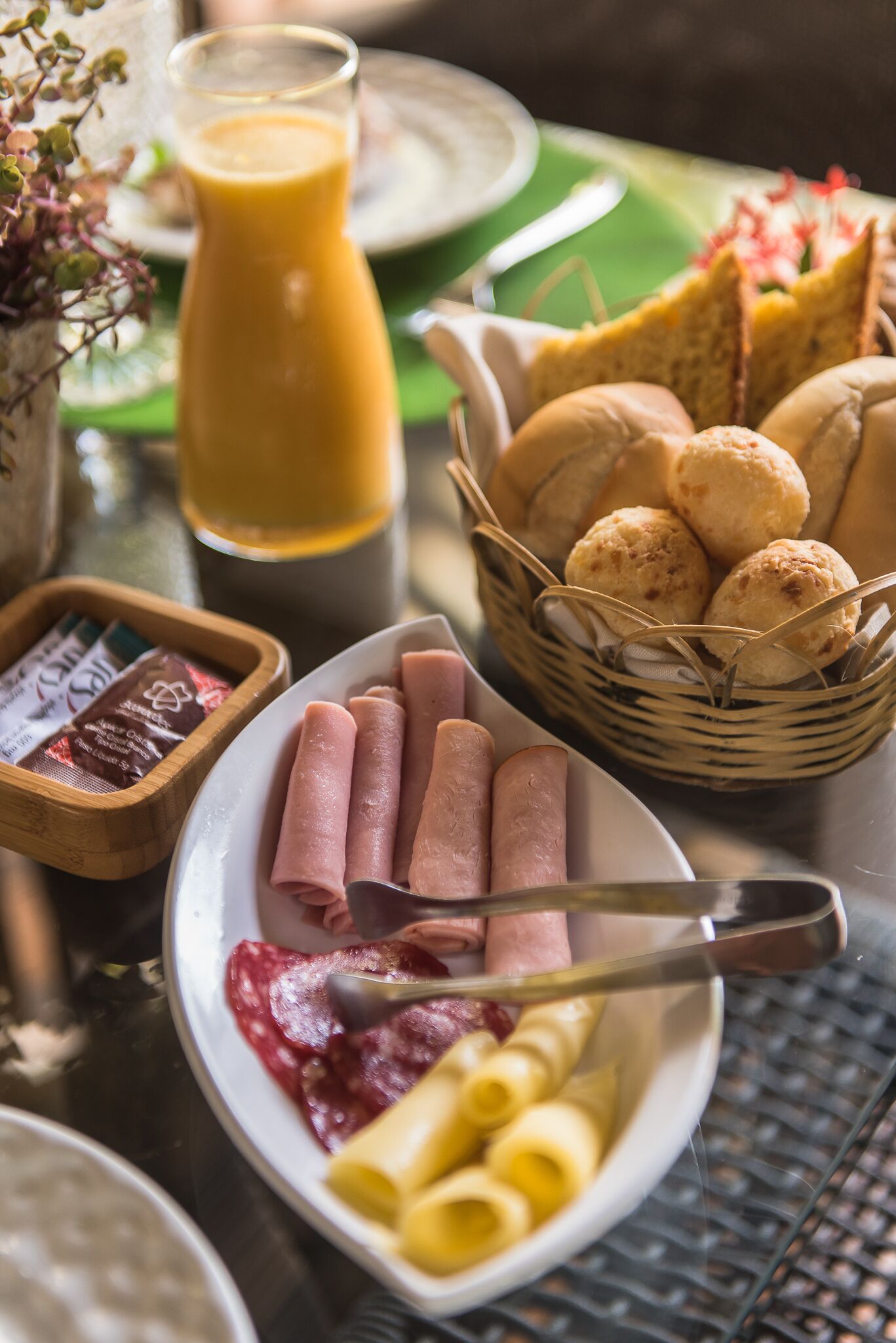 Uma mesa com alimentos, incluindo pão, pastelaria e um prato de enchidos.