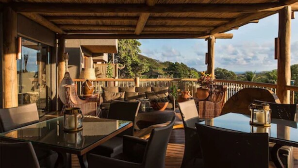 An outdoor seating area with tables and chairs, overlooking a scenic landscape. - Pousada Maria Bonita Noronha (Fernando de Noronha)