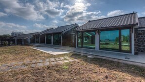 A row of modern houses with large glass windows and stone facades, set in a grassy area with a clear sky. - Penghu Bay Resort (Magong)