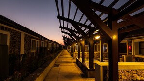A covered outdoor area with stone walls and wooden beams, featuring a pathway and seating areas. - Penghu Bay Resort (Magong)