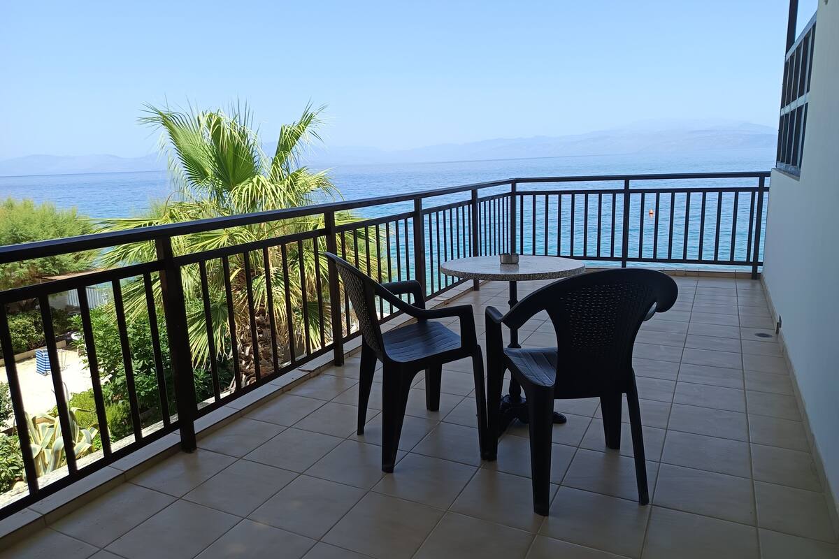 Un balcón con vistas al mar, una mesa redonda y dos sillas.