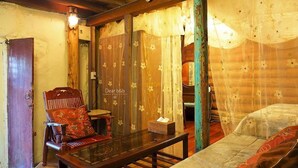 A cozy room with a wooden chair, a small table, and a bed with floral curtains. - Qi Tang Lane (New Taipei City)