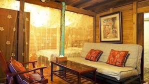 A cozy room with a wooden ceiling, a sofa with patterned cushions, a wooden chair, and a table with a tissue box. - Qi Tang Lane (New Taipei City)