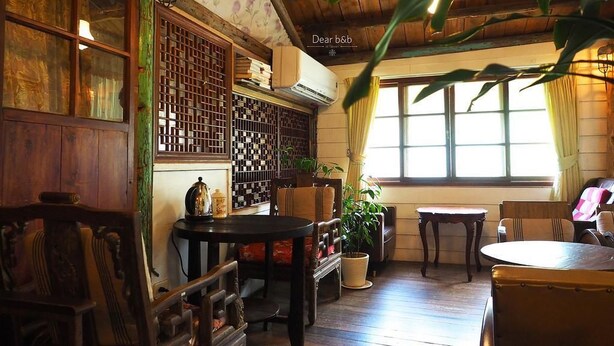 A traditional room with wooden furniture, a large window, and a decorative screen. - Qi Tang Lane (New Taipei City)