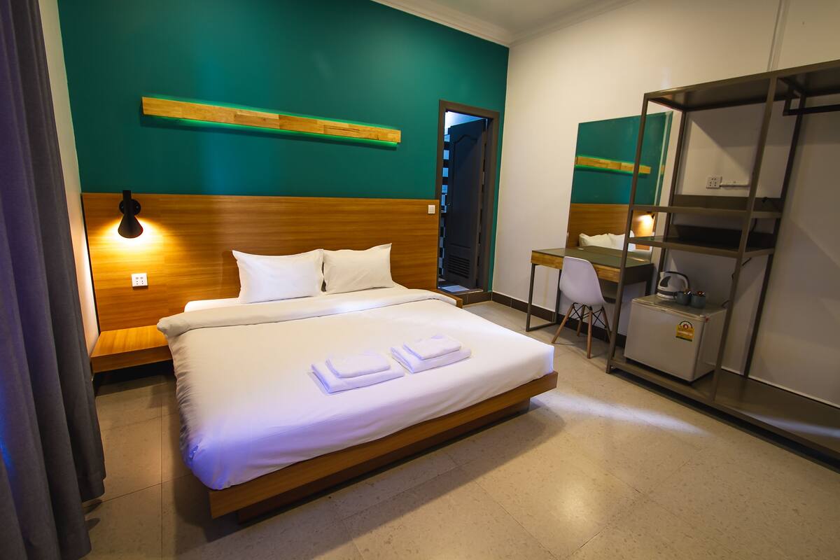 Une chambre d’hôtel comprenant un lit, une table de chevet, un bureau, une chaise et une armoire.