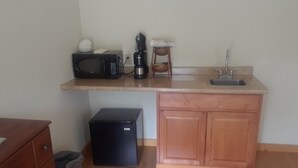 A compact kitchen with a microwave, coffee maker, sink, and a small trash bin. - Mt. Baker Hotel (Concrete)