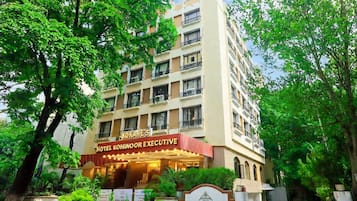 A multi-story hotel building with balconies and a sign indicating it is the 'Hotel Kokanoor Executive.'
