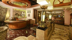 A hotel lobby with a marble floor, a central bar area, and a large decorative ceiling light. - Kohinoor Executive (Pune)