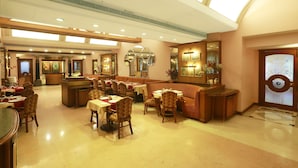 A spacious hotel lobby with multiple seating areas, a reception desk, and a large mirror. - Kohinoor Executive (Pune)