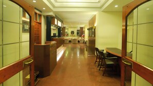 A hotel lobby with a reception desk, a seating area with chairs, and a dining table. - Kohinoor Executive (Pune)
