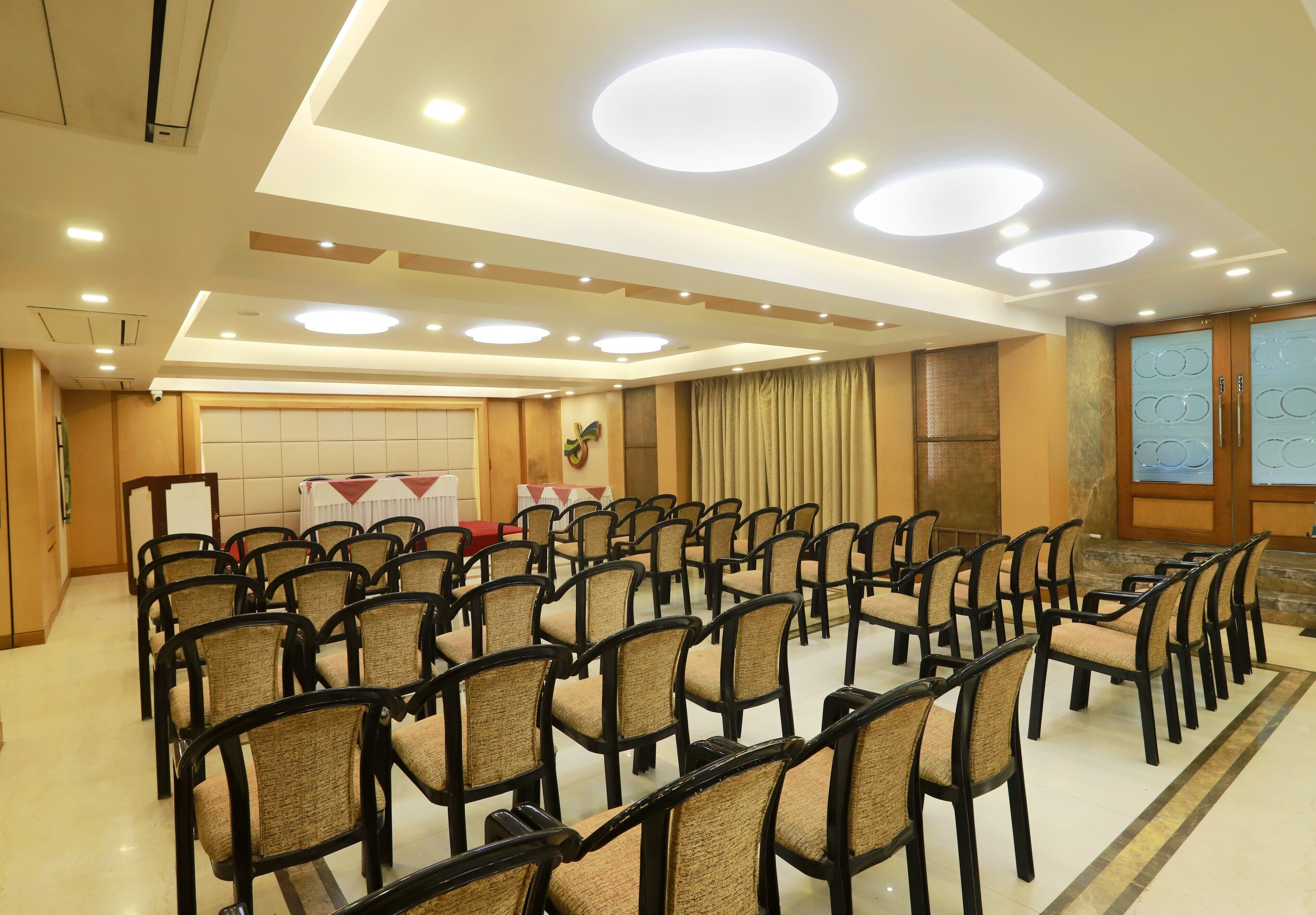 Un salón de conferencias con filas de sillas, un atril y un amplio ventanal con cortinas.