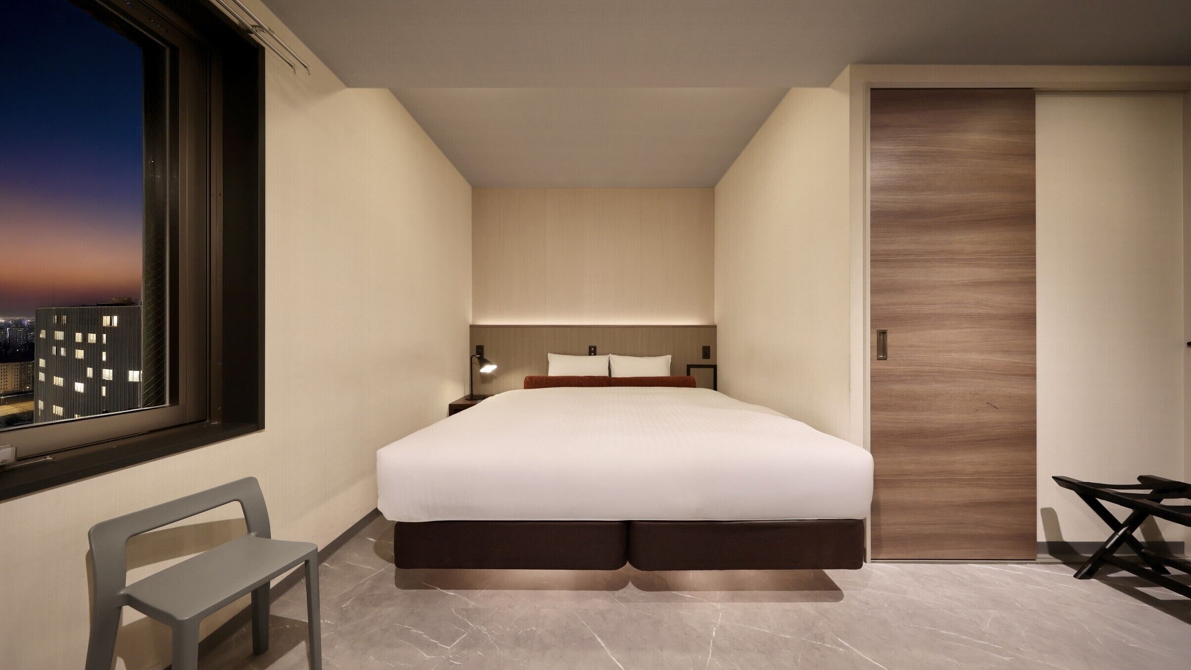 Une chambre d’hôtel moderne, dotée d’un grand lit, d’un bureau et d’une chaise.
