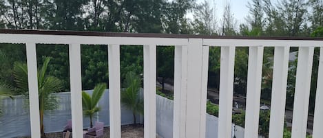 A wooden deck with a white railing, a small pool, and outdoor furniture.