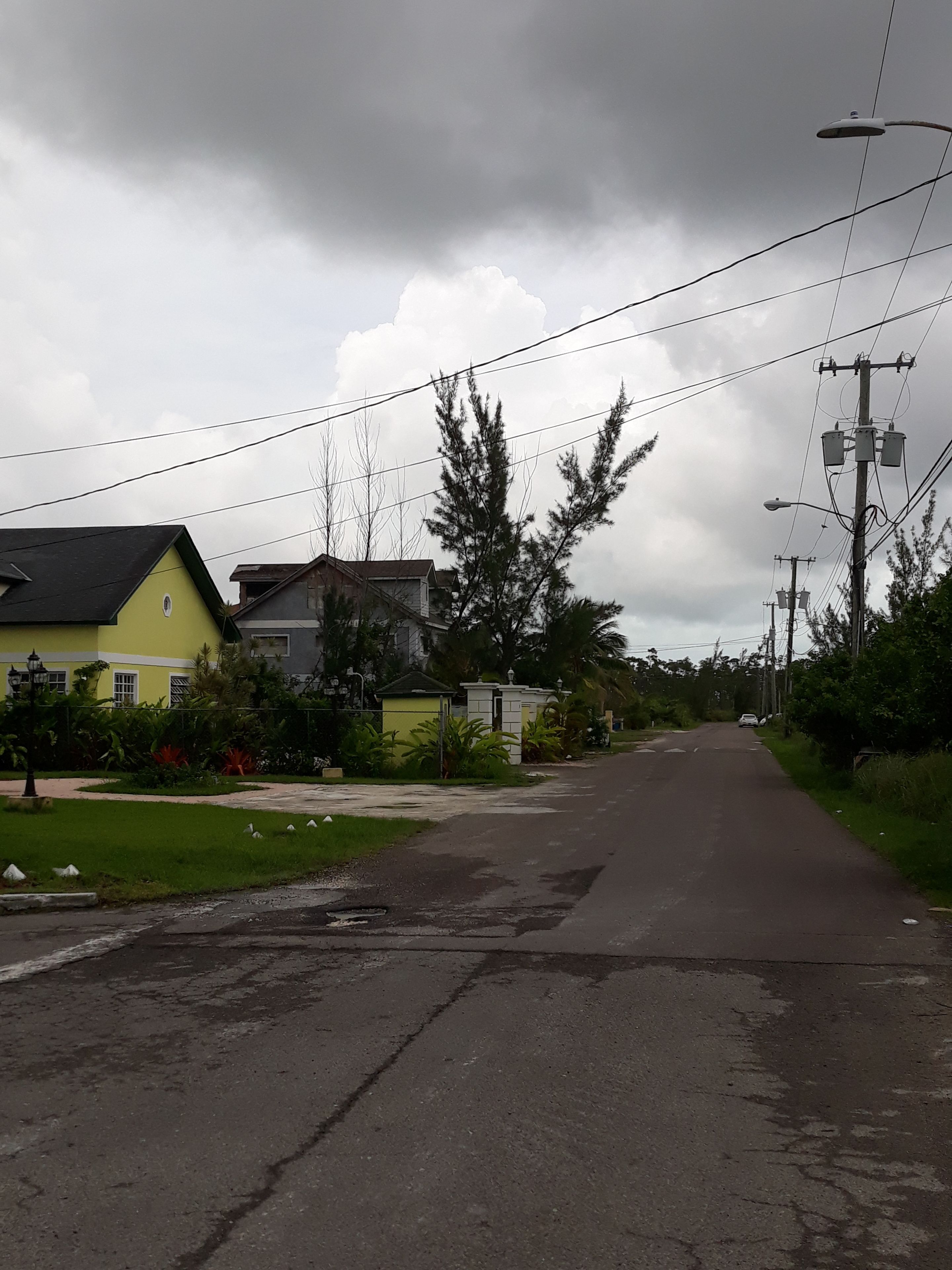 Une rue résidentielle bordée de maisons, de poteaux électriques et de lignes électriques aériennes.