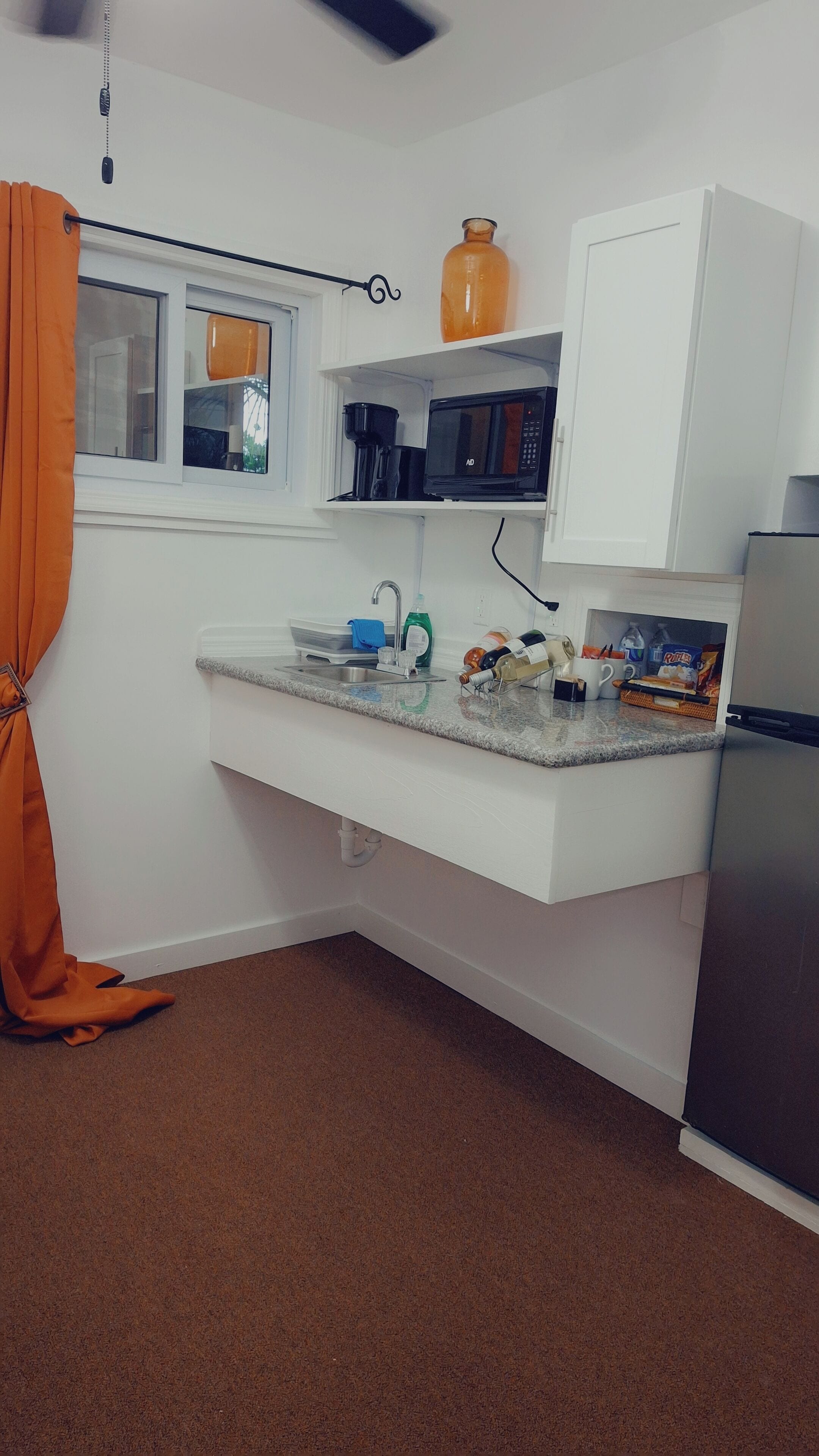 A compact kitchen with a built-in microwave, a coffee maker, and a refrigerator.