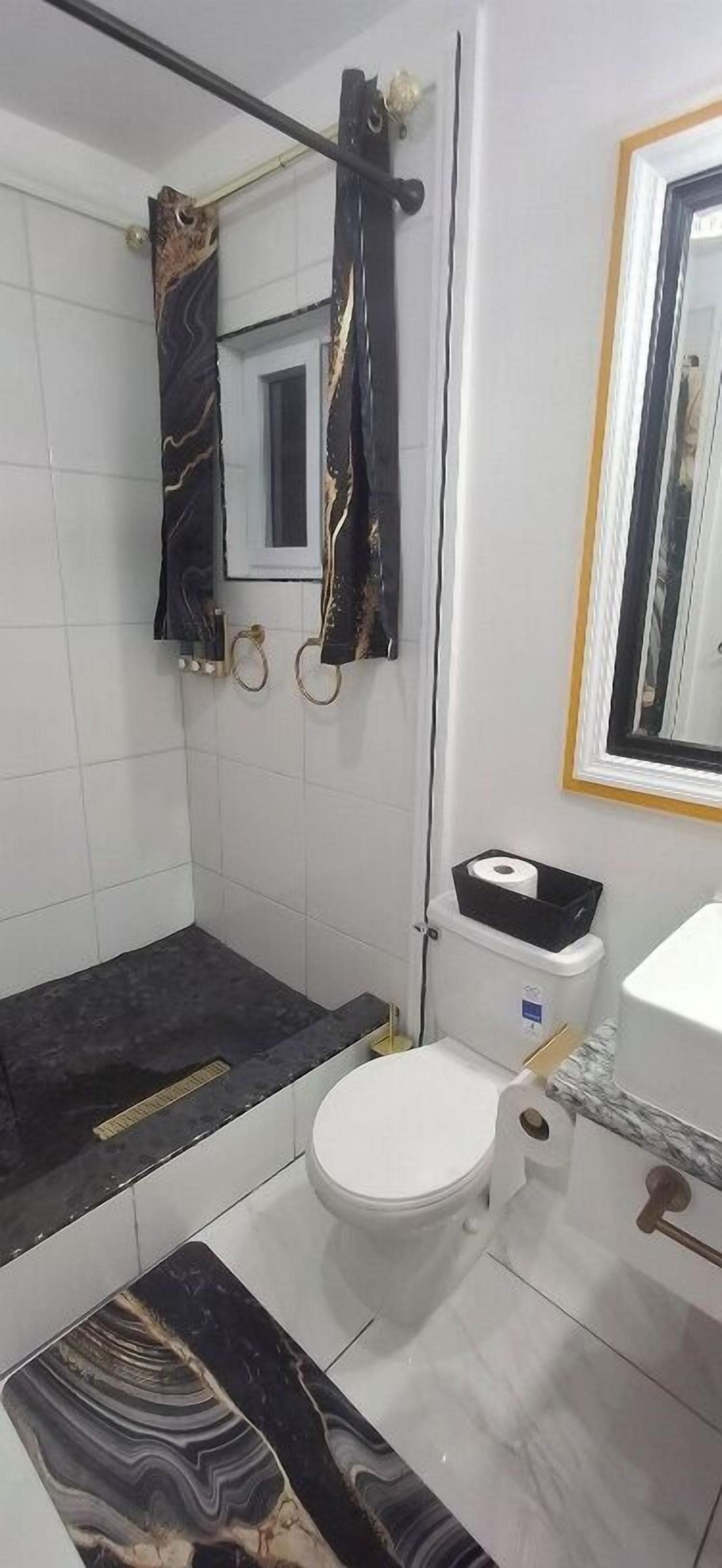 Une salle de bain comprenant des toilettes, un espace douche, un miroir et un lavabo.