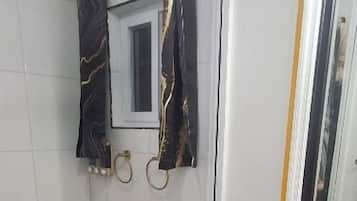 Une salle de bain comprenant des toilettes, un espace douche, un miroir et un lavabo.