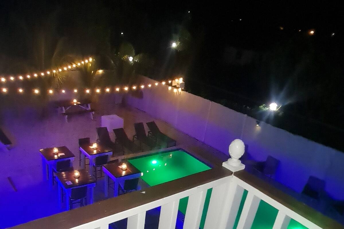 Una terraza con mesa de billar, sillas de descanso y luces colgantes.