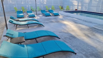 A poolside area with multiple lounge chairs and a small pool.