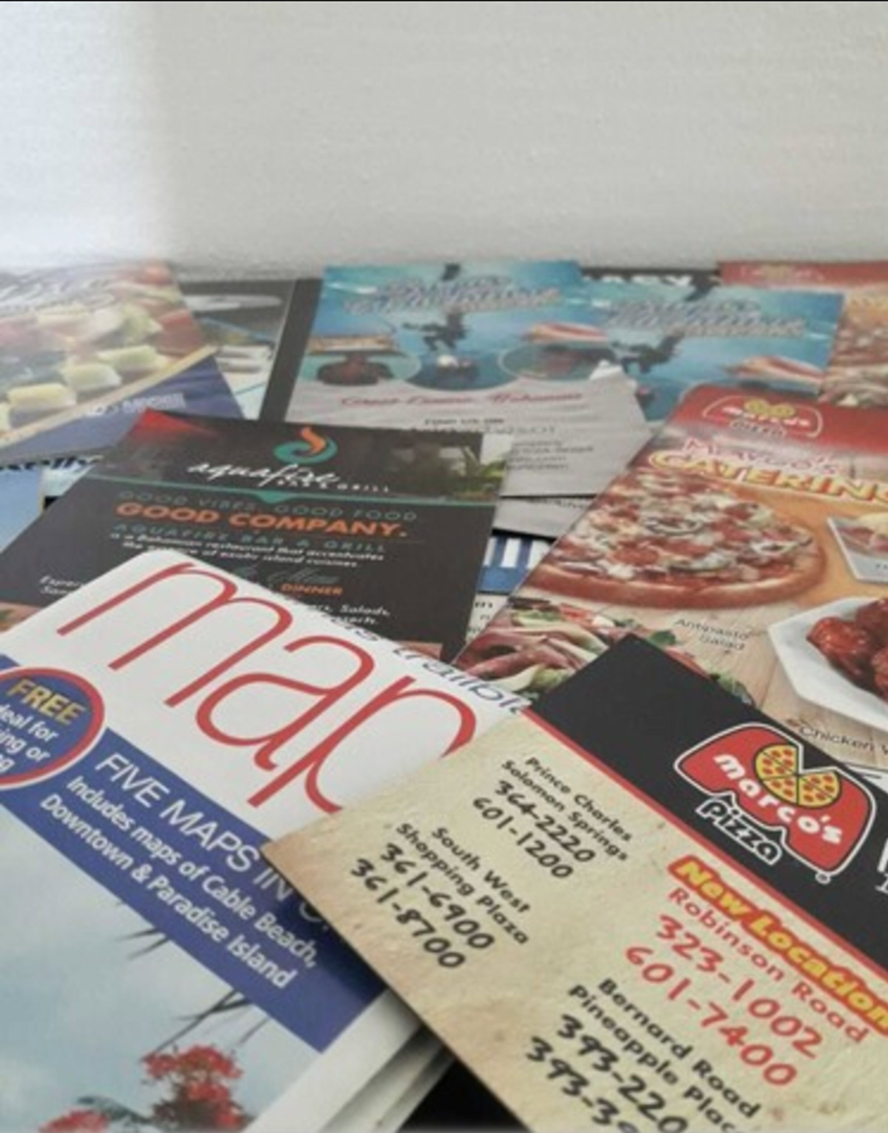 A collection of printed materials including a map, a pizza menu, and a restaurant advertisement.