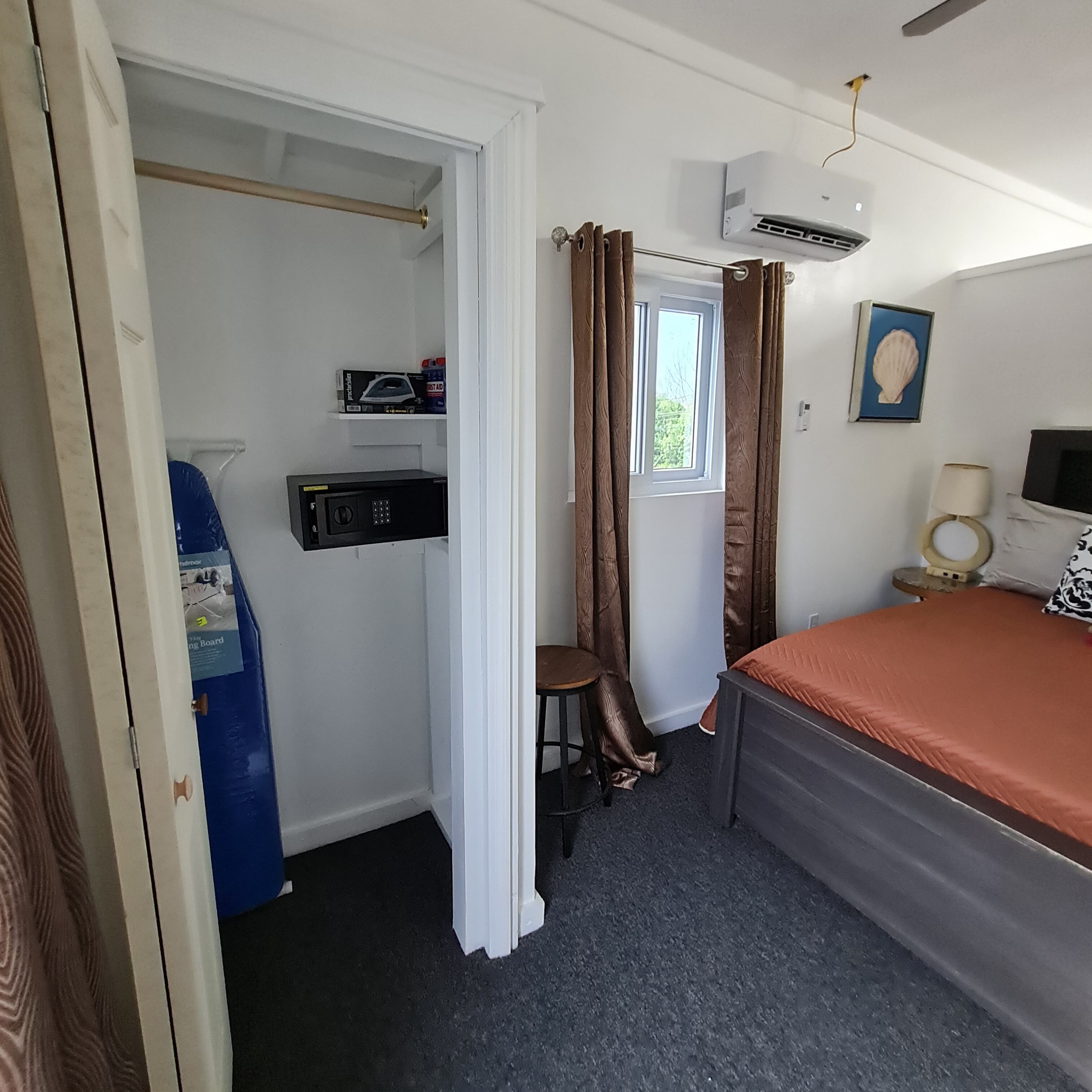 Une chambre à coucher comprenant un lit, un bureau, une chaise, une armoire et un appareil de climatisation.