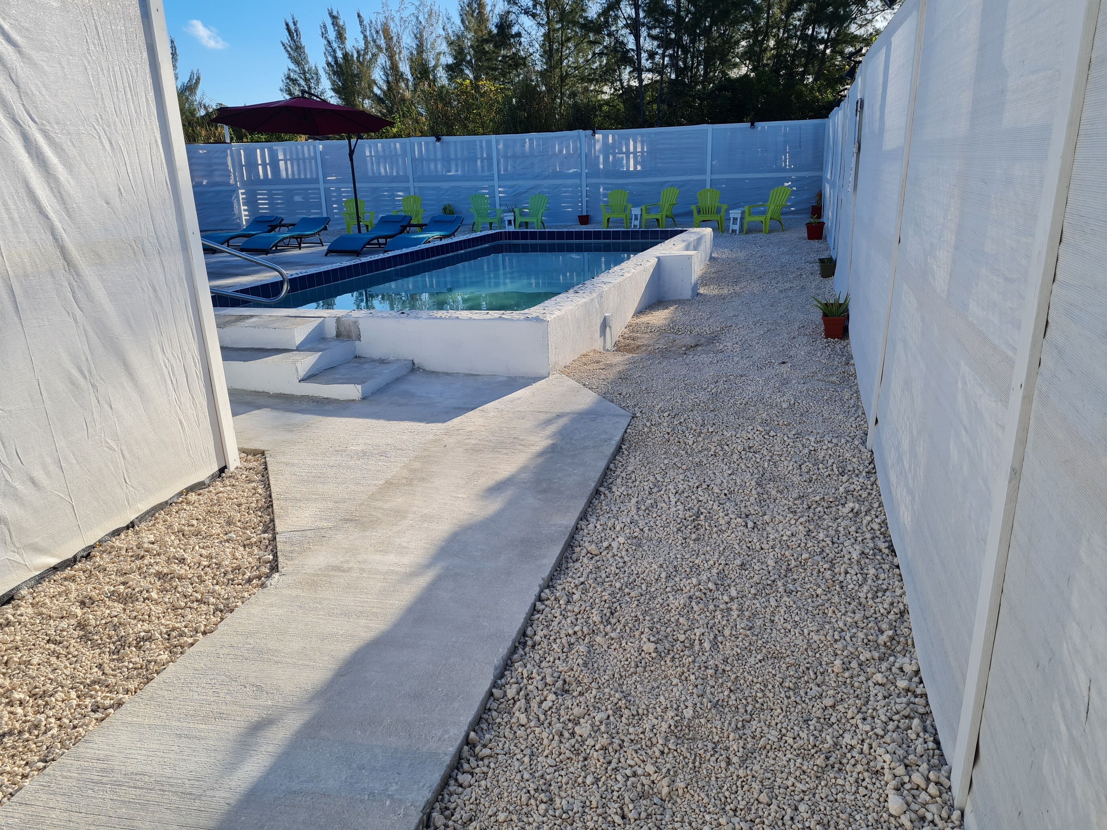 Une piscine avec des chaises longues et un espace patio couvert.