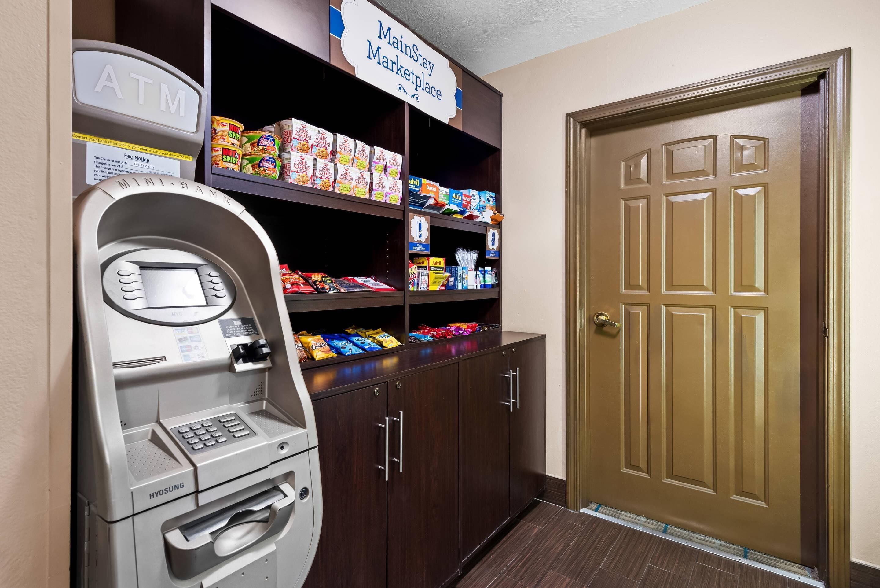 An ATM, snack shelves, and a door in a hallway.