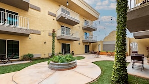 Un cortile con un’area salotto circolare, mobili da esterno e un edificio con numerosi balconi.