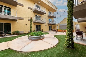 A courtyard with a circular seating area, outdoor furniture, and a building with multiple balconies. - Mainstay Suites El Centro I-8 (El Centro)