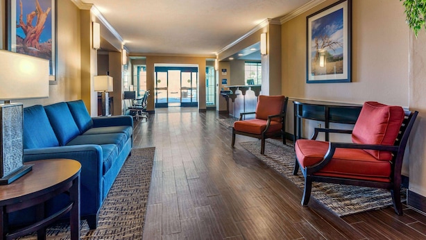 Una hall d'albergo con un divano blu, una poltrona rossa e un tavolino in legno.
