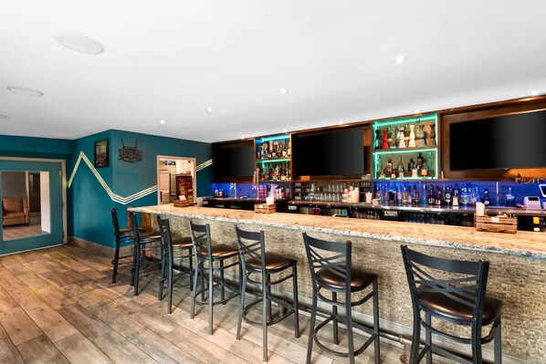 A bar area with a long counter, multiple stools, and a variety of bottles and glasses. - Mainstay Suites El Centro I-8 (El Centro)