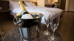 A hotel room with a bed, a minibar with a bottle of champagne and two glasses, and a small table. - TN & CO Hotel (Mugla)