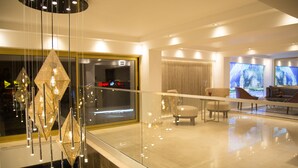 A modern interior with a glass railing, a chandelier, a large window, and a seating area. - TN & CO Hotel (Mugla)
