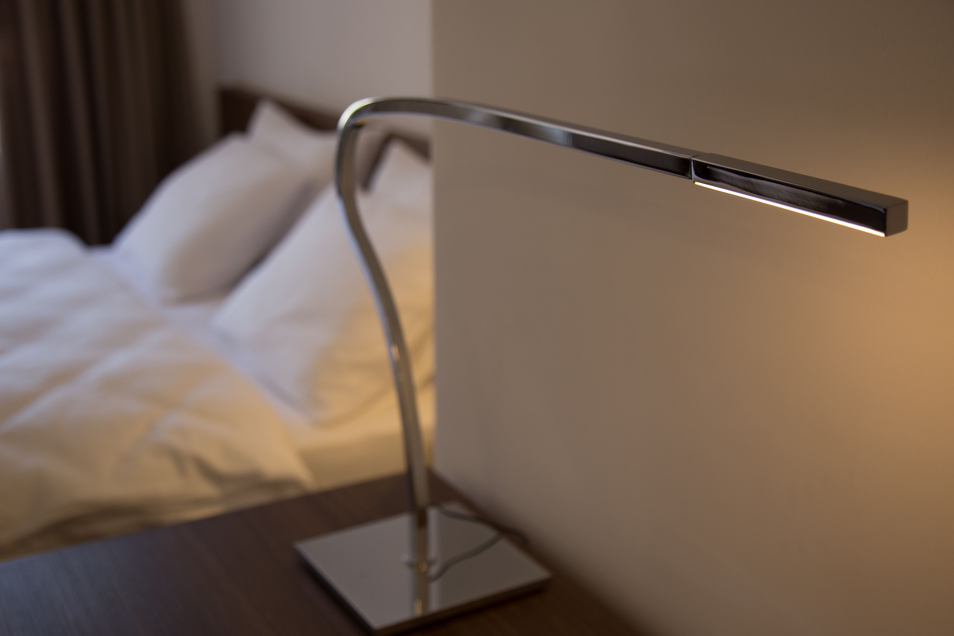 A modern bedside table with a sleek, metallic lamp.