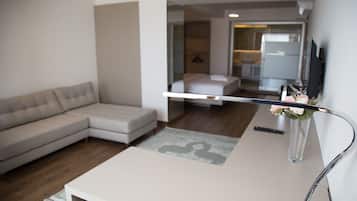A modern living room with a sofa, a coffee table, and a TV mounted on the wall.